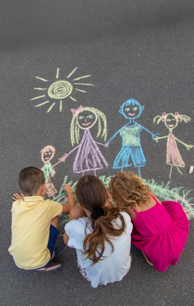 Children drawing a chalk family on the pavement