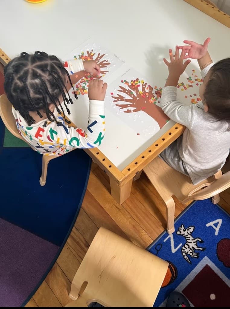 Children making fall tree crafts at a classroom table
